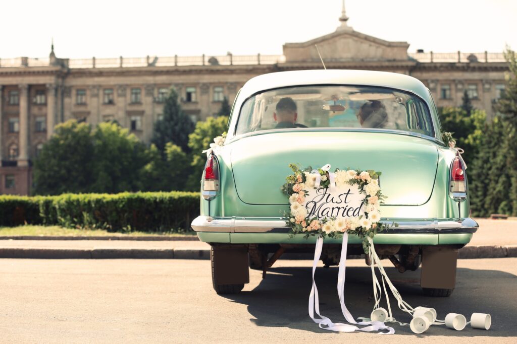 Bride and groom sitting in gateway car with "Just Married" decoration on back